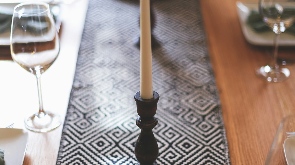 black candle holder with white candle on brown wooden table