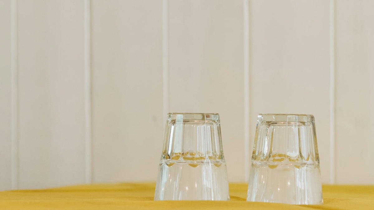 2 clear glass bottles on yellow table