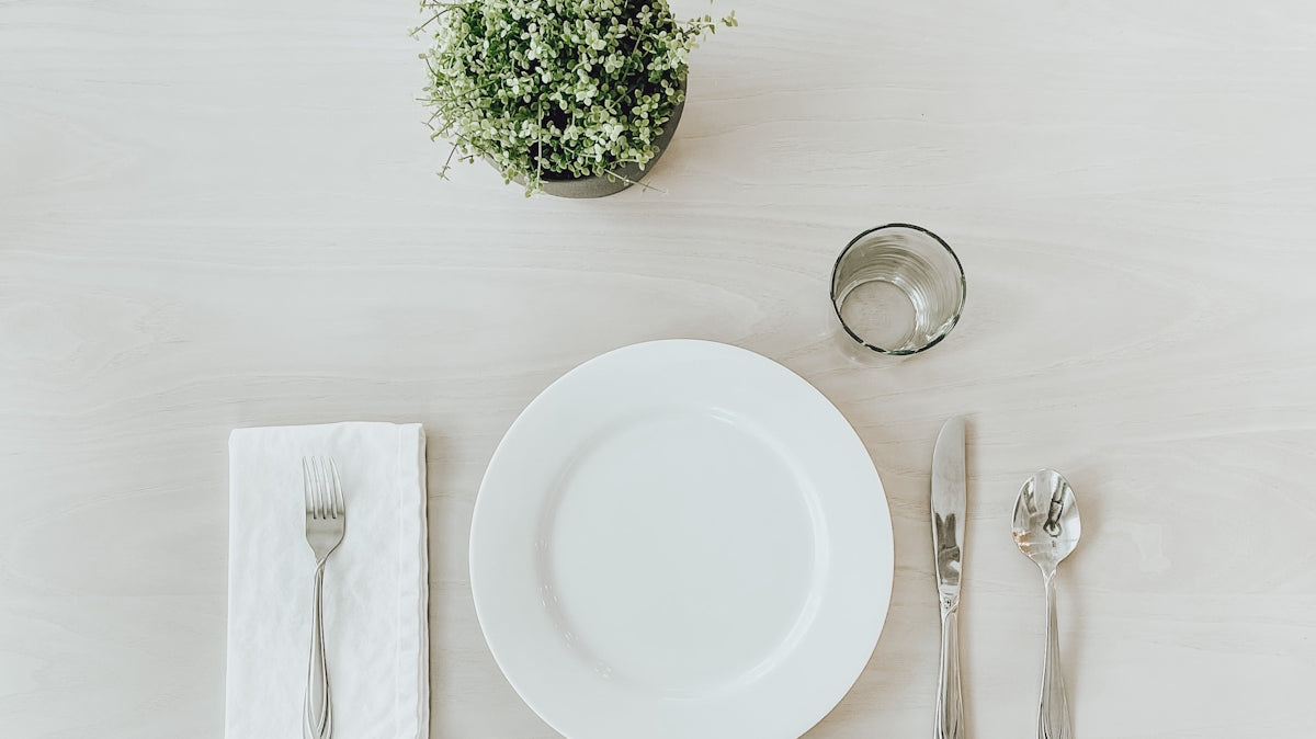 white ceramic plate beside stainless steel fork and bread knife on white table