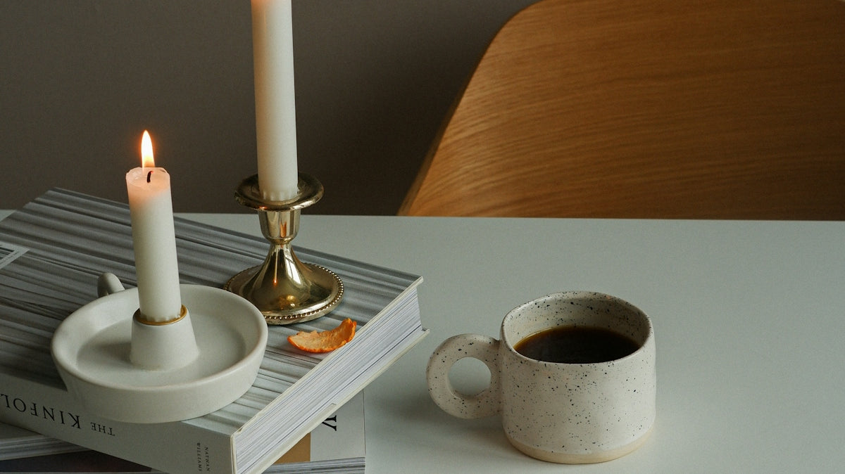 a table topped with a cup of coffee and two candles