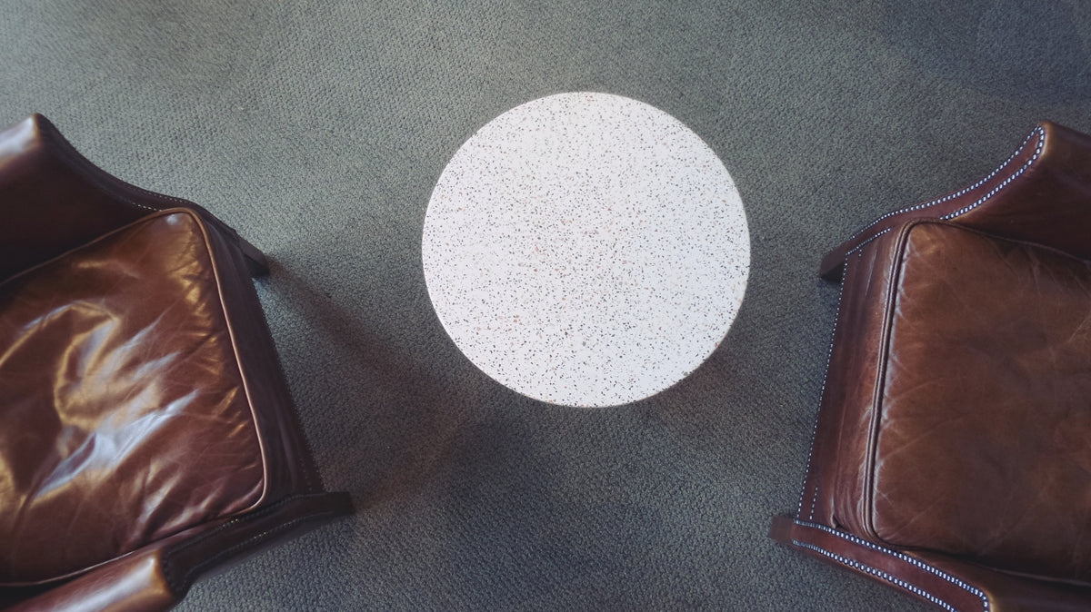 two leather chairs and a round table on a carpet