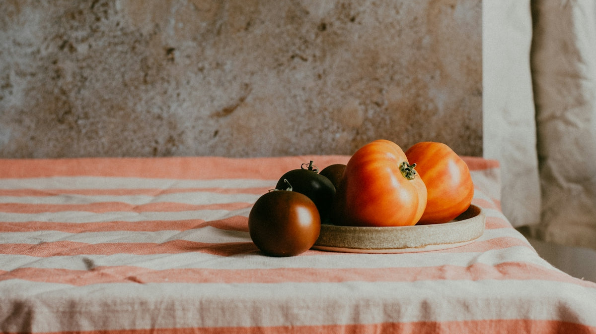 a plate of tomatoes on a striped tablecloth