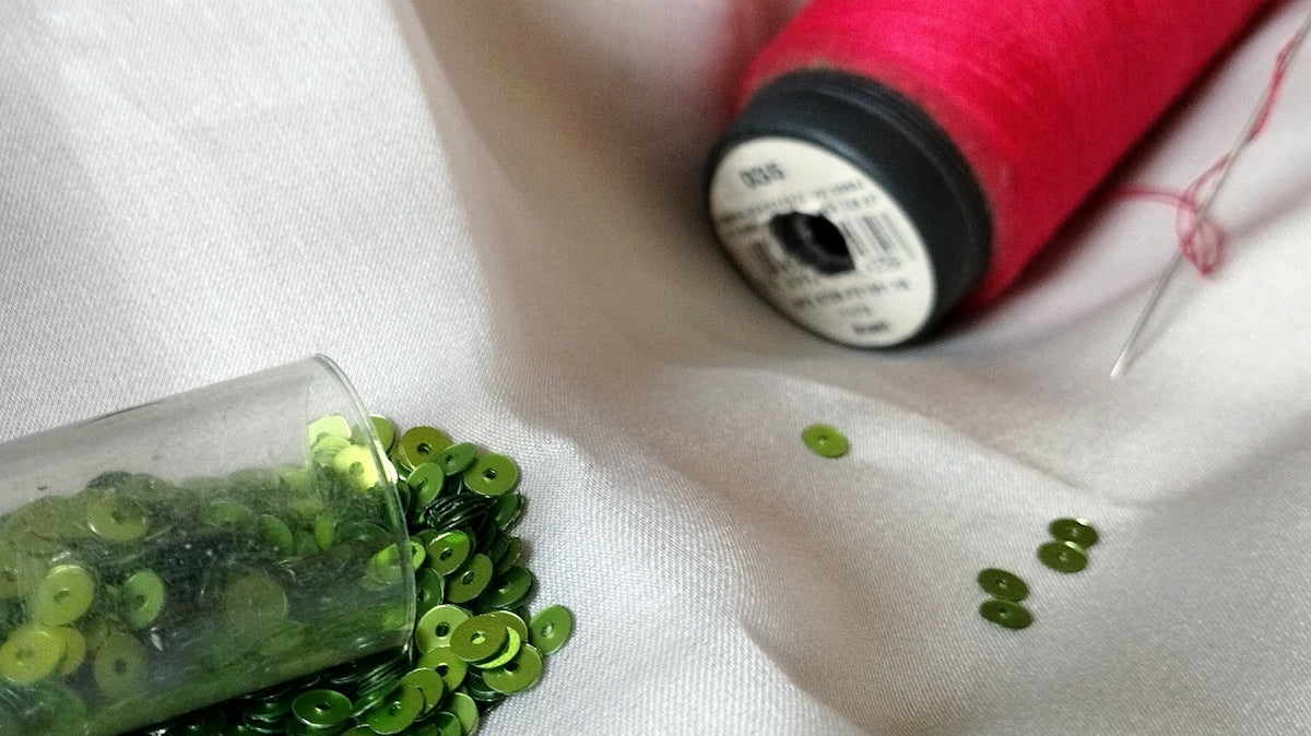 a spool of thread next to a spool of green beads
