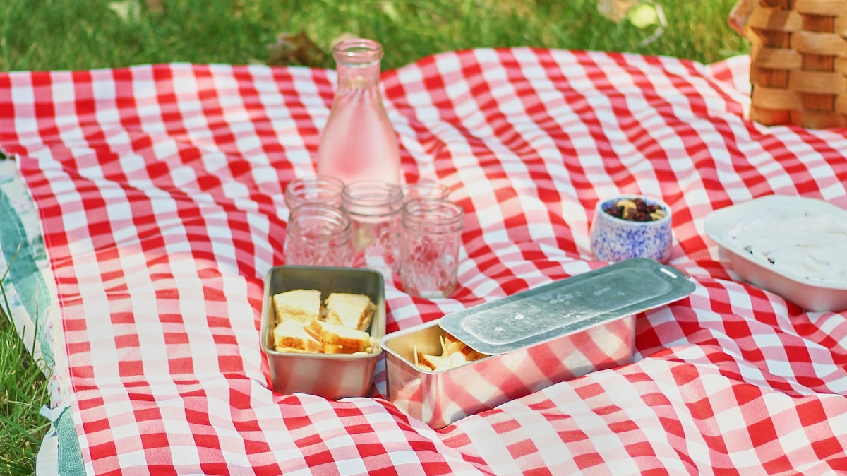 A picnic blanket with food and drinks on it