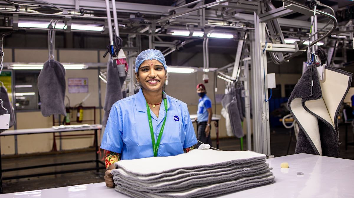 A factory worker smiles in a manufacturing plant.