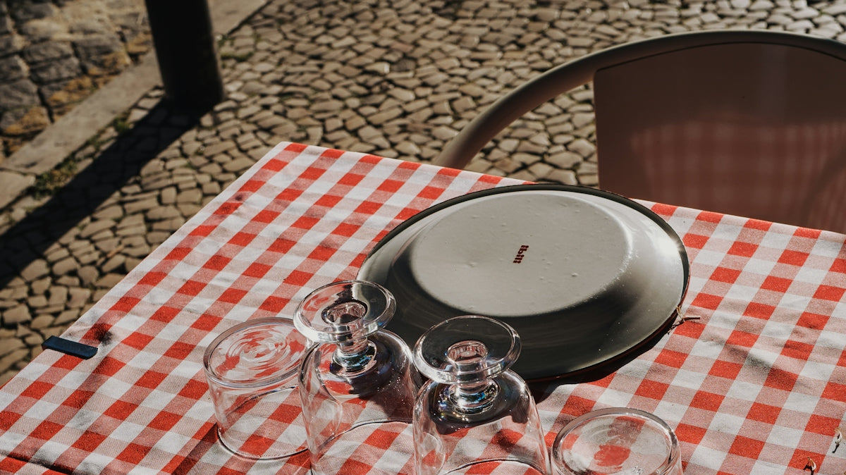 Plates and glasses sit on a checkered tablecloth.