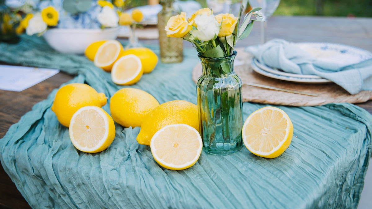 Lemons and yellow flowers on a teal tablecloth.