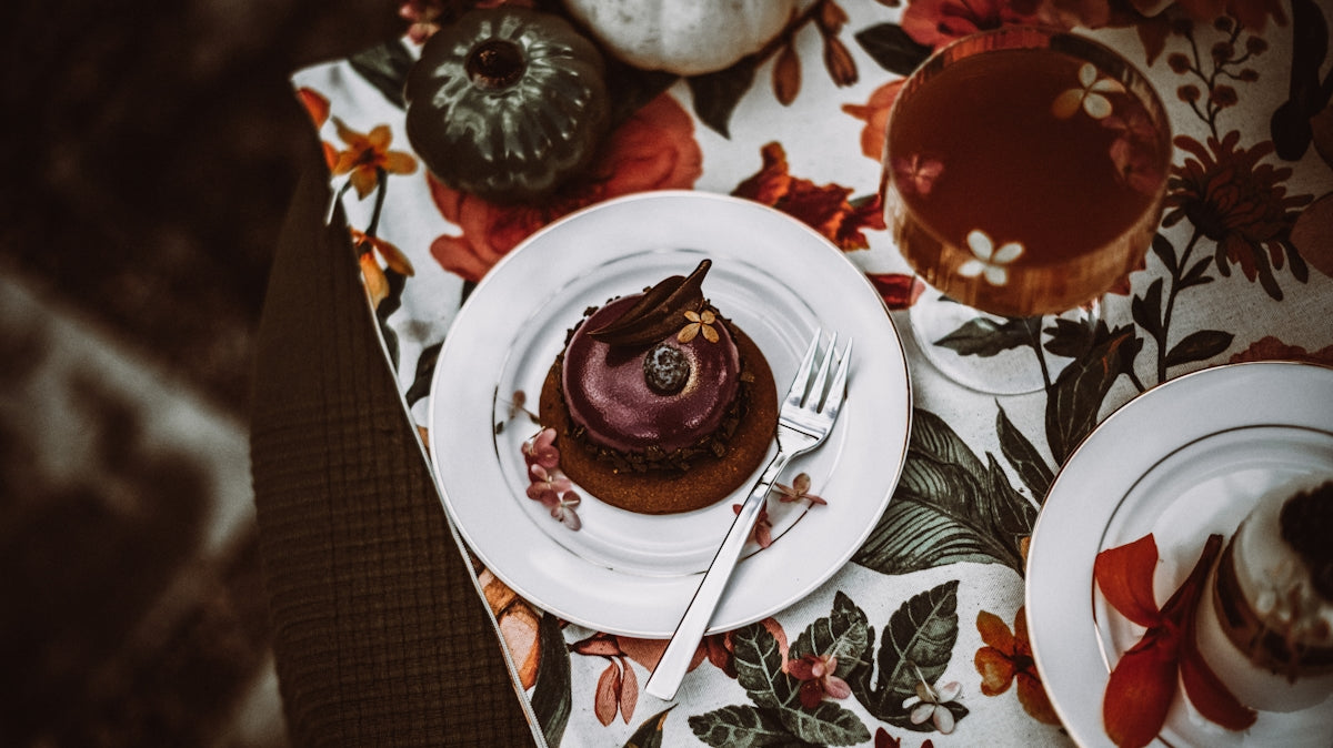 Chocolate dessert on a floral tablecloth, featuring rich frosting and decorative elements.