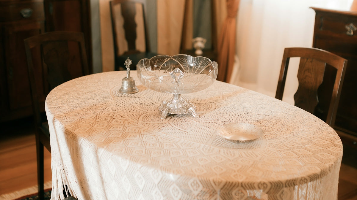 Oval dining table with ornate lace tablecloth and chairs