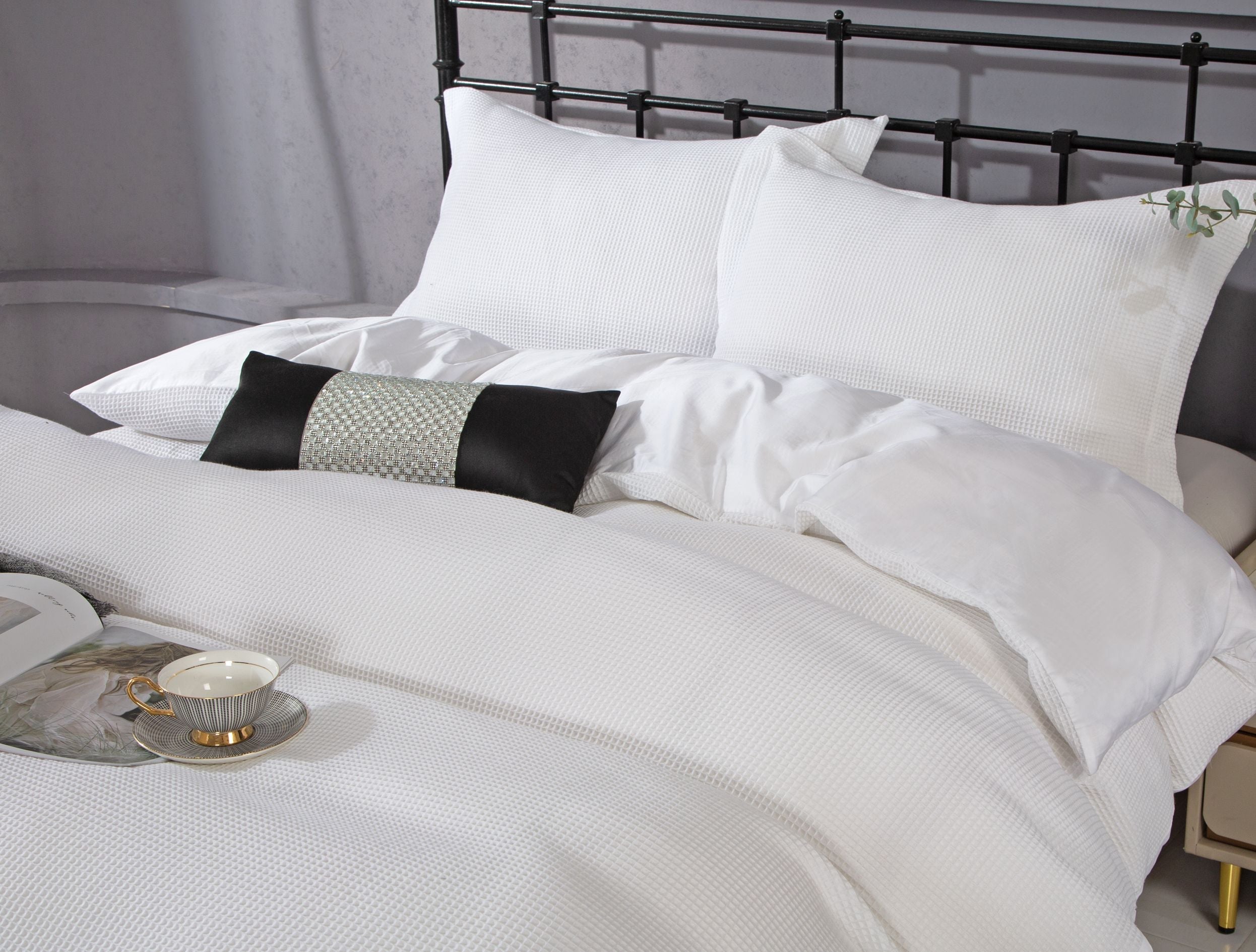 White waffle-textured cotton sateen duvet set with matching shams on a metal bed