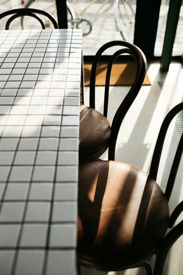 Brown leather dining chairs beside a tiled table in a bright cafe setting.