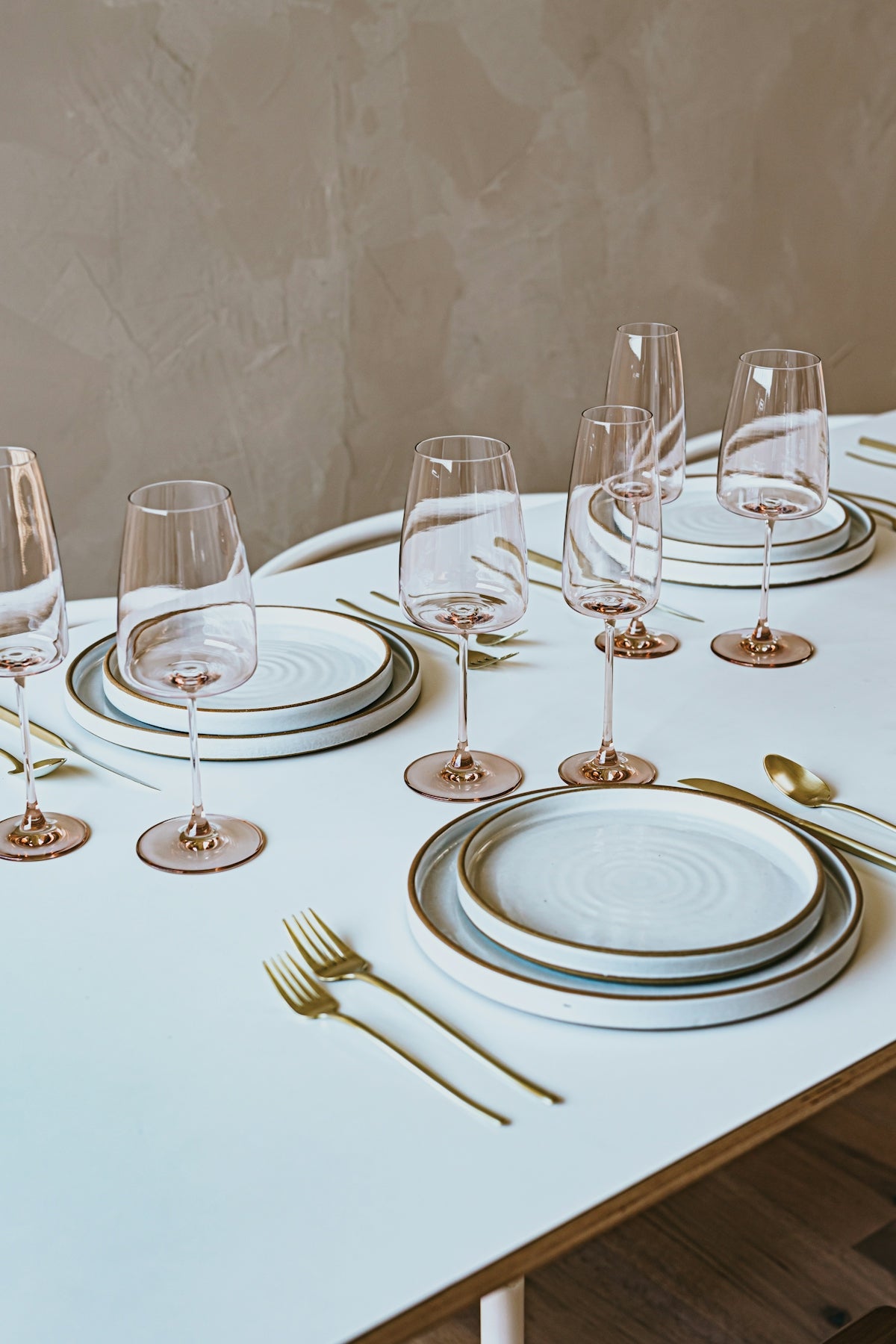 Elegant dinnerware set featuring white plates with gold accents and crystal wine glasses.
