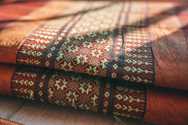 Handwoven textile featuring intricate patterns in earthy tones and green accents.