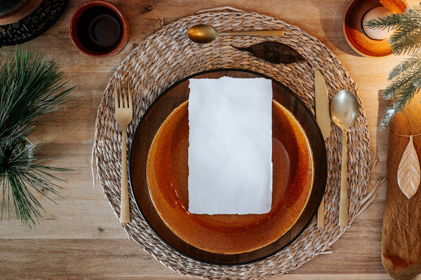 Elegant dinner setting featuring a blank menu card on a rustic plate with gold utensils.