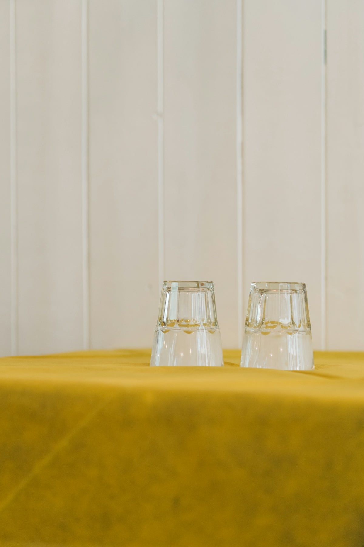 Clear glass tumblers on a yellow tablecloth, showcasing their elegant design.