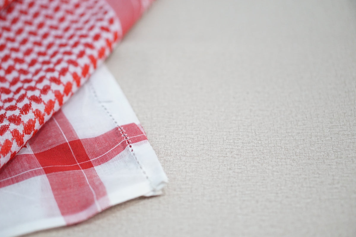 Red and white keffiyeh scarf with a textured background.