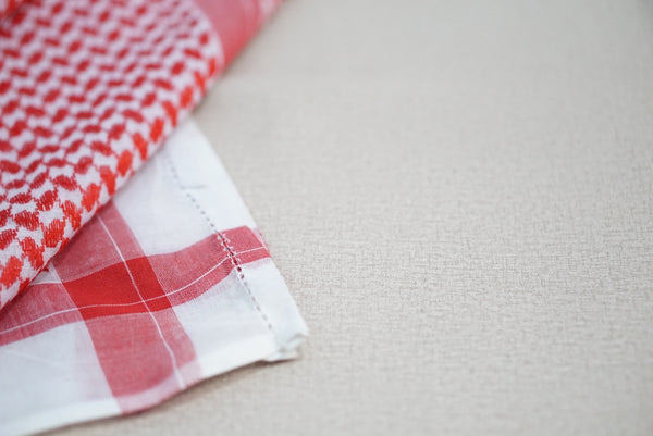 Red and white keffiyeh scarf with a textured background.