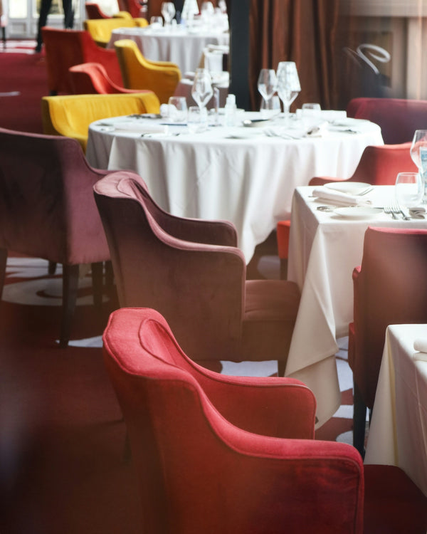 Colorful restaurant chairs in red, yellow, and purple around elegantly set tables.