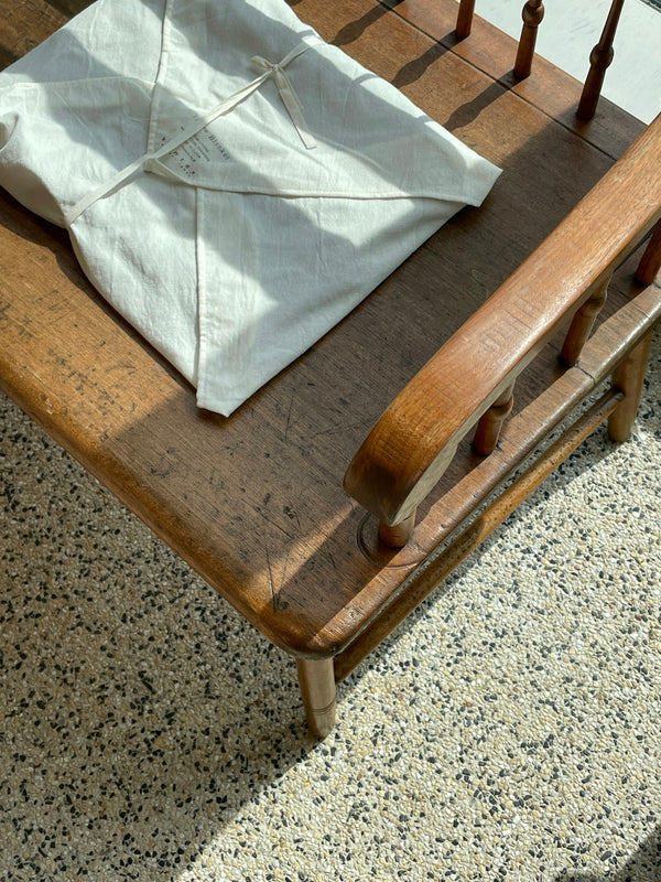 Linen storage bag on a wooden table, showcasing a rustic design and natural textures.