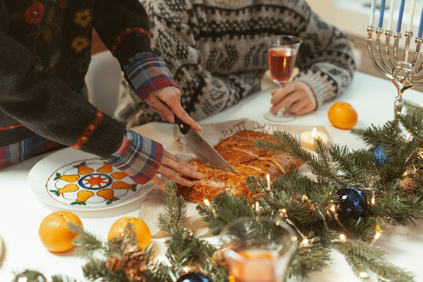 Festive holiday gathering with a person slicing a dessert on a decorated table.