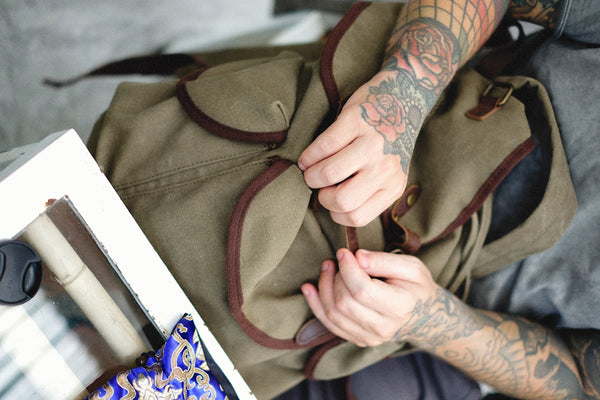 Canvas Backpack with Brown Accents, featuring a person adjusting the straps.
