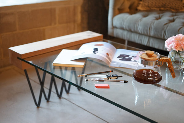 Modern Glass Coffee Table featuring a sleek design with decorative items and a magazine.