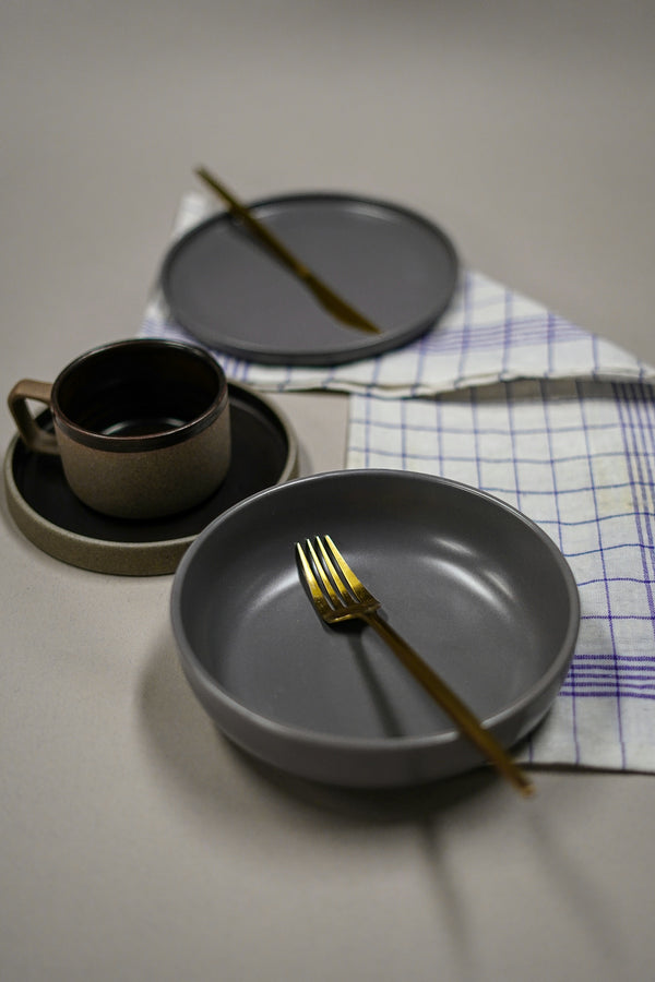 Elegant gray dinnerware set featuring a bowl and plate with gold fork and cup.