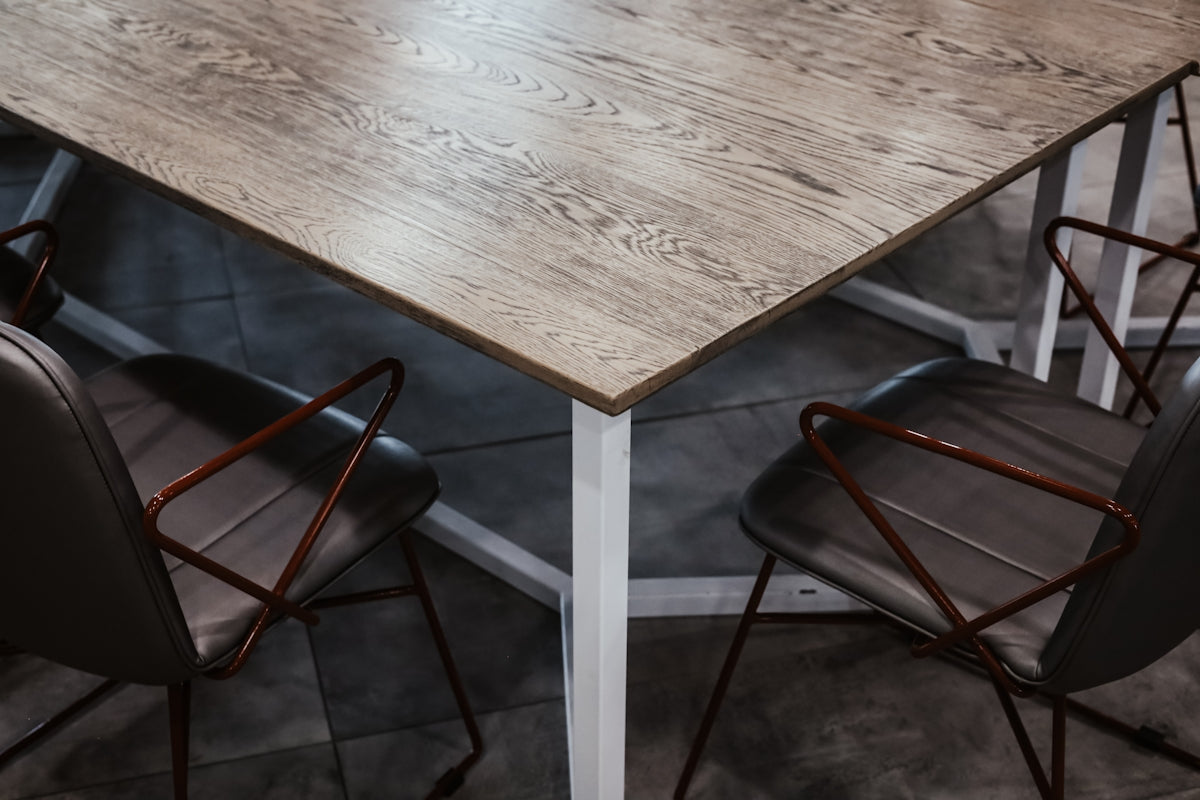 Modern dining table with a wooden top and sleek metal legs, surrounded by stylish black chairs.