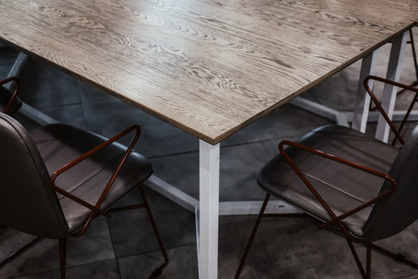 Modern dining table with a wooden top and sleek metal legs, surrounded by stylish black chairs.