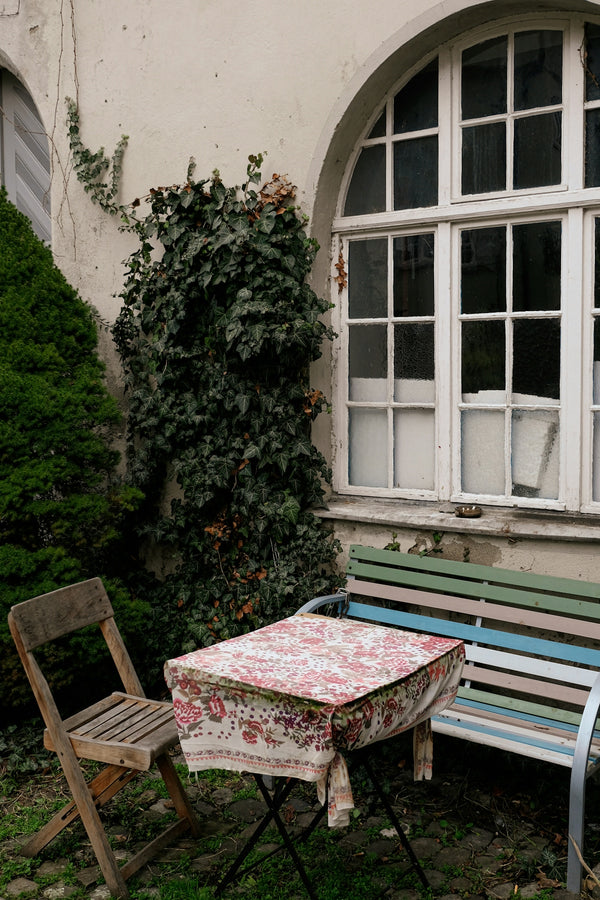 Garden table with floral tablecloth set in a cozy outdoor space.