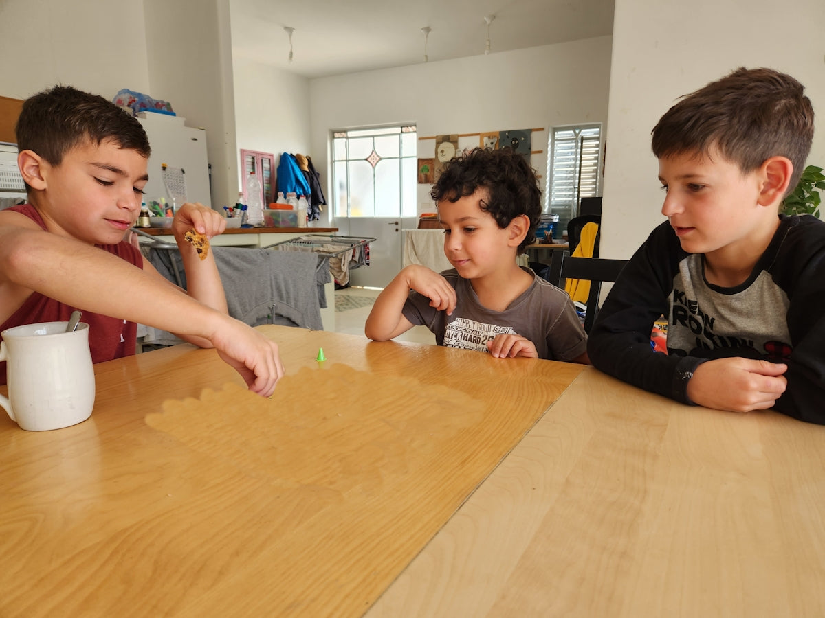 Kids playing with colorful game pieces on a wooden table.