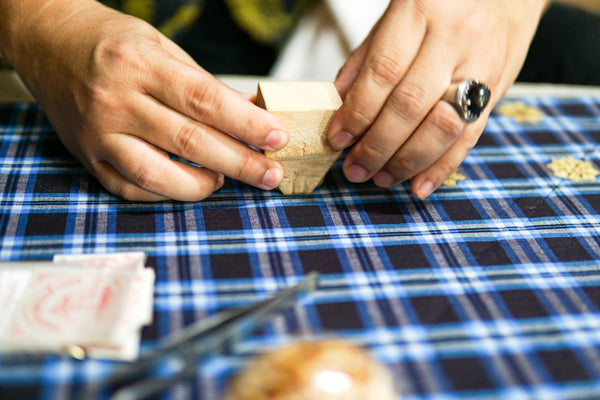 Handcrafted wooden box being assembled on a blue plaid tablecloth.