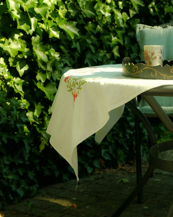 Tablecloth with floral design on a garden table surrounded by green ivy.