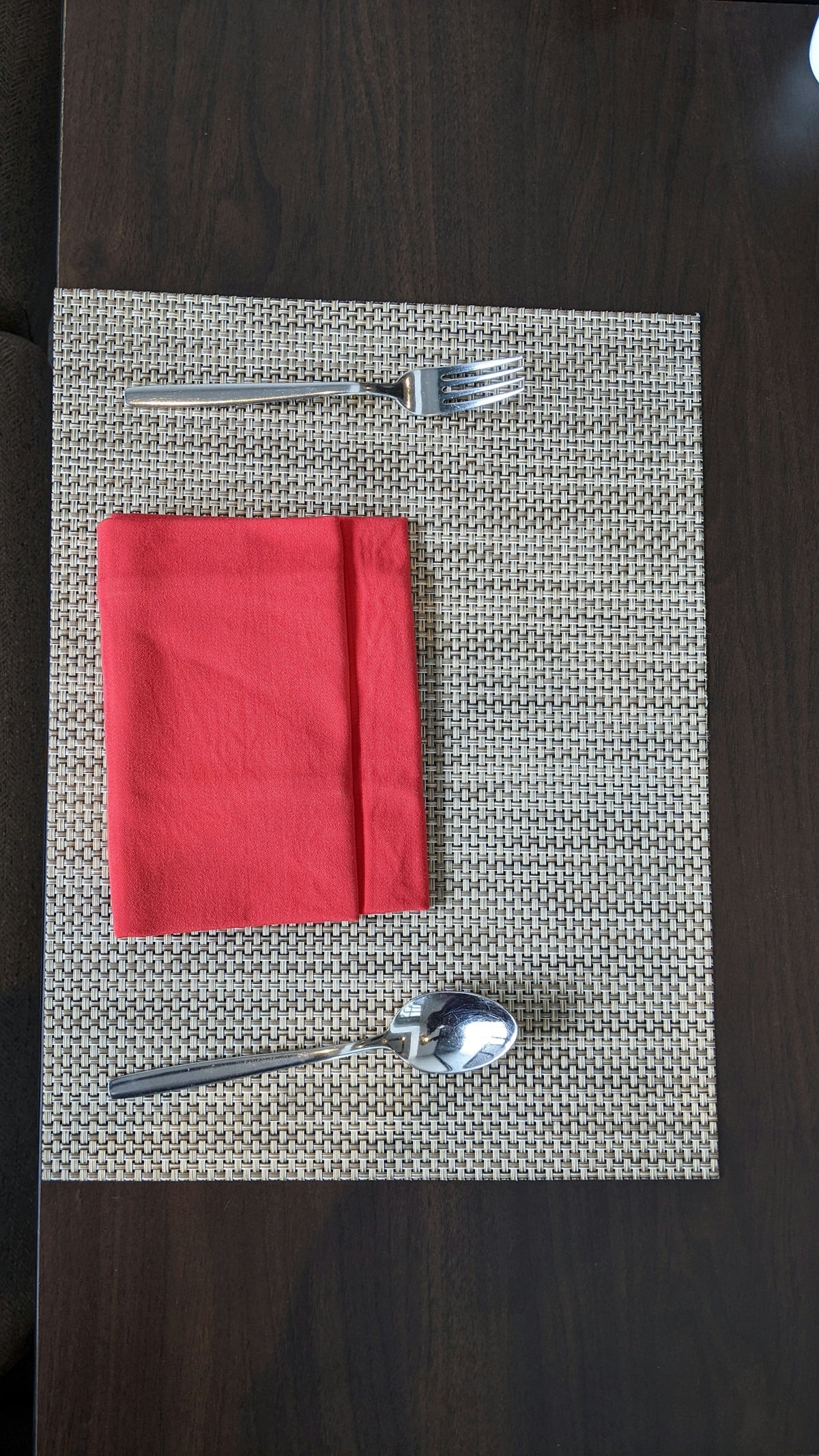 Red Napkin on Woven Placemats with Fork and Spoon.