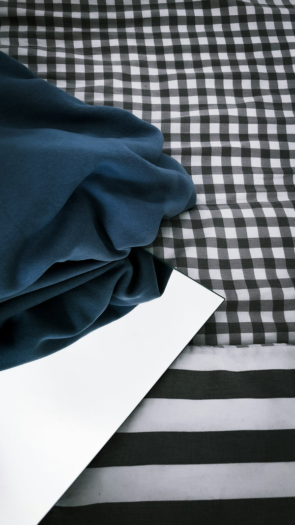 Navy Blue Fabric draped over a black and white checkered background with a mirror reflecting the texture.