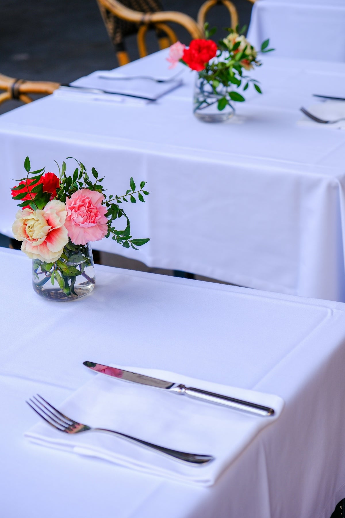 Table setting with elegant floral centerpiece featuring red and pink flowers.