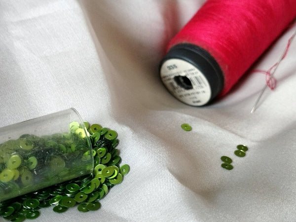 Green Sequin Crafting Supplies with Pink Thread for DIY Projects.