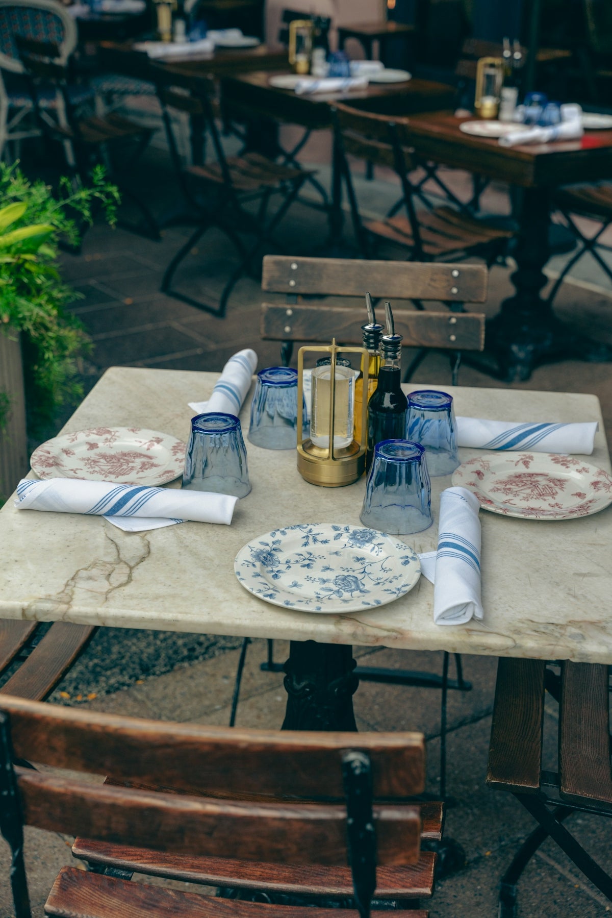 Dining table setup with floral plates and blue glasses for an outdoor restaurant experience.