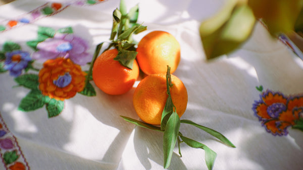 Fresh oranges on a colorful floral tablecloth, showcasing vibrant colors and natural textures.