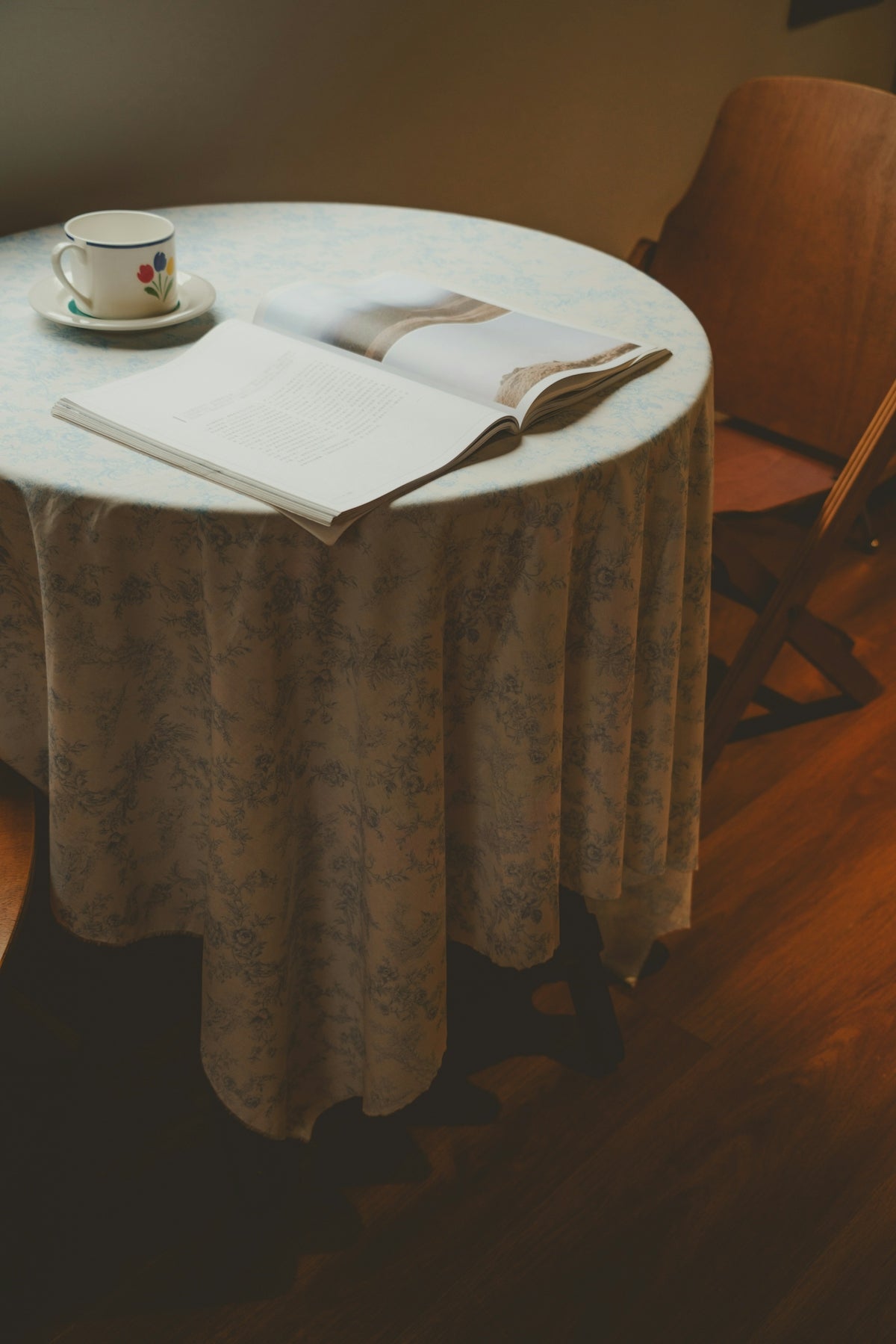 Floral Tablecloth on Round Table with Open Book and Coffee Cup.
