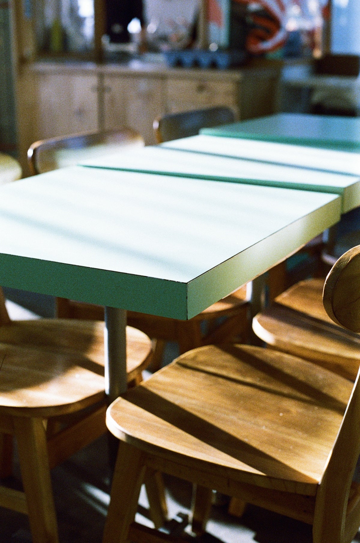 Mint green dining table with wooden chairs in a cozy setting.