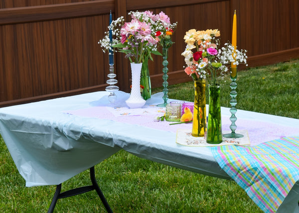 Colorful floral centerpiece for a table setting featuring vases and candles.