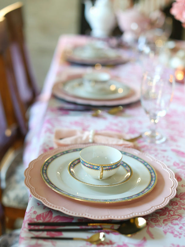 Elegant porcelain dinnerware set featuring pink plates and a decorative teacup.