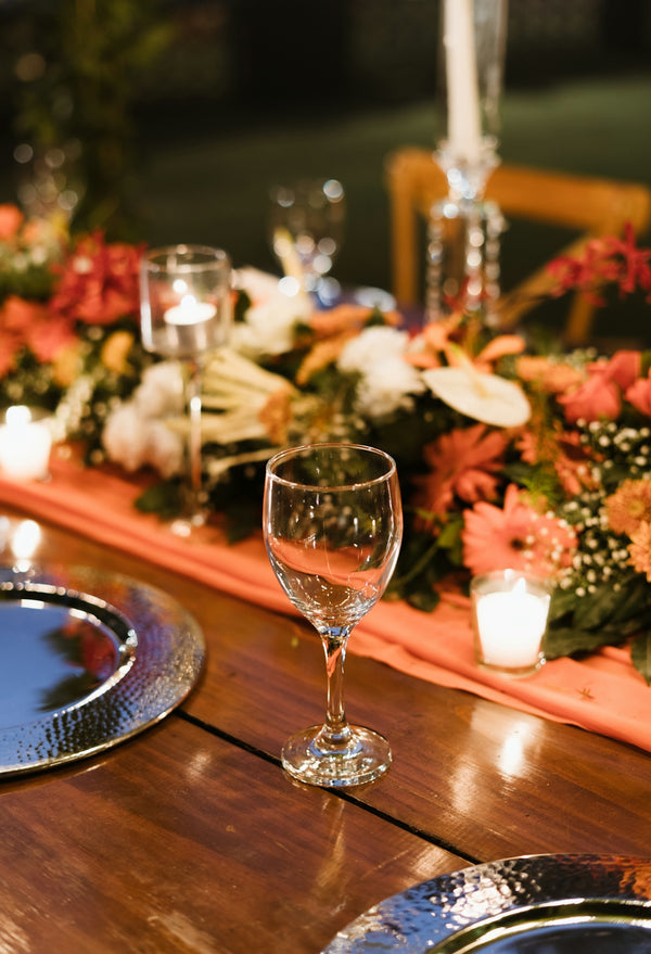 Elegant glassware for dining, featuring a clear wine glass on a beautifully decorated table with floral arrangements.
