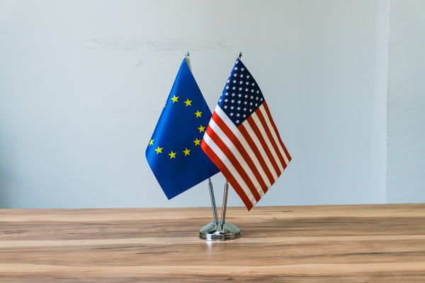 European Union and United States flags displayed on a table, symbolizing international relations.