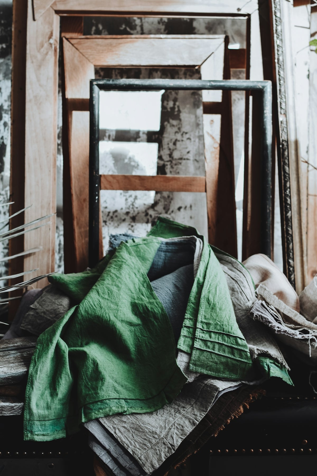 Green linen draped over rustic frames and antique frames