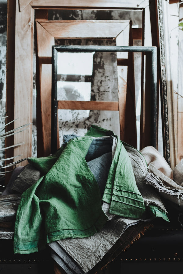 Green linen draped over rustic frames and antique frames