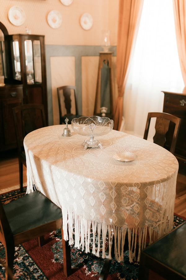 Elegant dining table with a lace tablecloth, set for a meal in a cozy dining room.