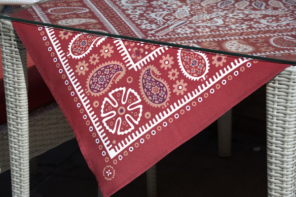 Red paisley tablecloth featuring intricate patterns and designs on a glass table.