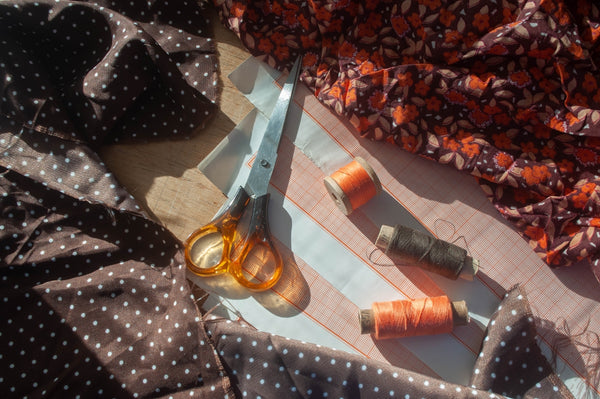 Scissors and spools of thread on fabric.